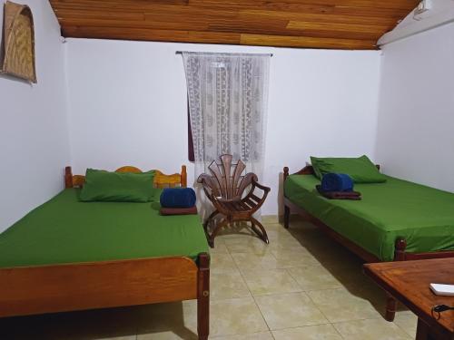a bedroom with two beds and a chair and a table at Malabar home stay in Jaffna