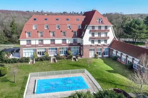 アルドロ・プラージュにあるL'Echapée Hardelot Vue Piscine - Piscine - Parking Résidenceの大きな建物で、目の前にスイミングプールがあります。