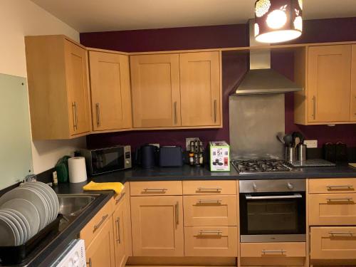 een keuken met houten kasten en een kookplaat met oven bij Morrisons 2 weeks plus city centre 2 bedroom Apt in Aberdeen