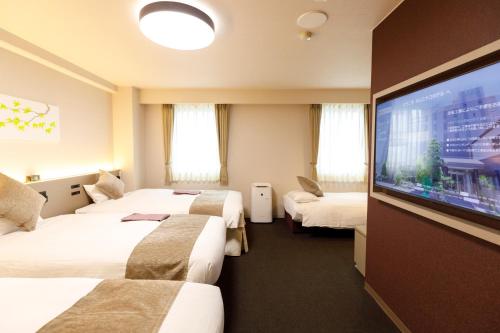 a hotel room with three beds and a flat screen tv at Inuyama Miyako Hotel in Inuyama