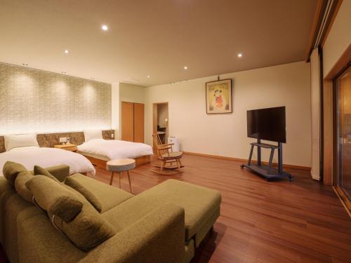 a bedroom with a couch and a bed and a television at Sekitaitei Ishida in Achi