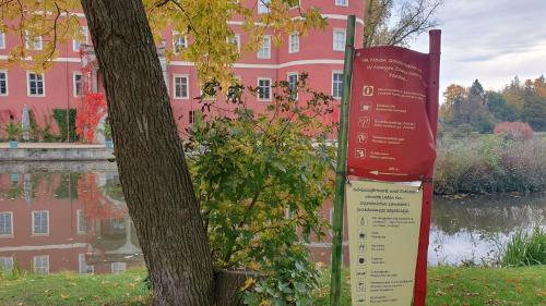 a tree and a sign in front of a pink building at Ruhige Unterkunft im Erdgeschoss ,Nähe Schloss & UNESCO-Geopark, Waldeisenbahn, Natur und Kultur direkt vor der Tür in Bad Muskau