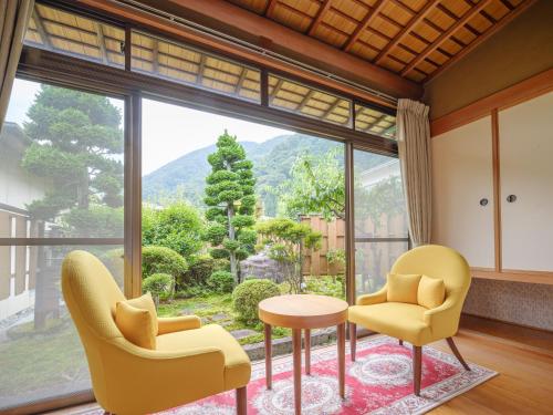 a living room with yellow chairs and a table and a large window at Sekitaitei Ishida in Achi