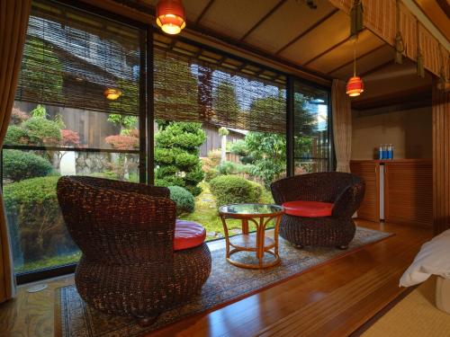 two chairs and a table in a room with a window at Sekitaitei Ishida in Achi