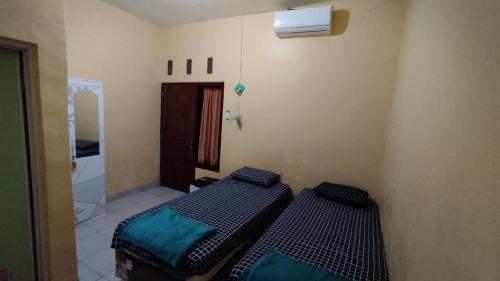 two beds in a room with a mirror at Amalia Guest House Banyuwangi in Ketapang