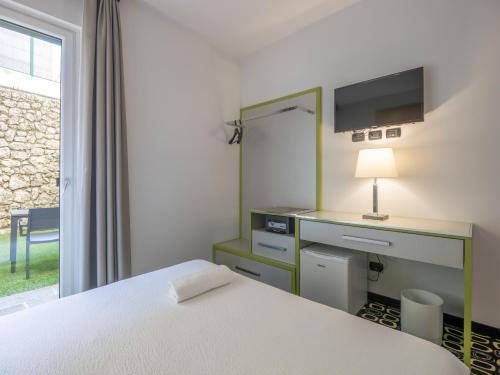 a bedroom with a bed and a desk and a window at San Valentino Hotel in Villa di Serio