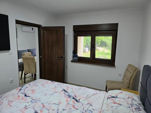 a bedroom with a bed and a chair and a window at Nova Panorama in Vrdnik