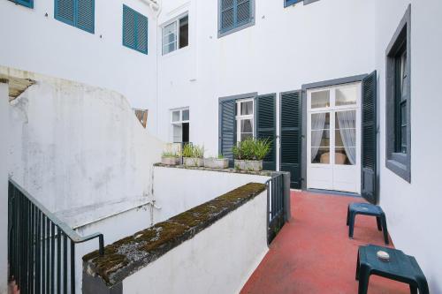 a courtyard of a white building with a stair case at Casa da Avó Guida in Ponta Delgada