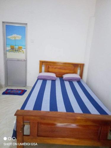 a bedroom with a bed with a blue and white stripes at Wasana Guest Yala in Kirinda