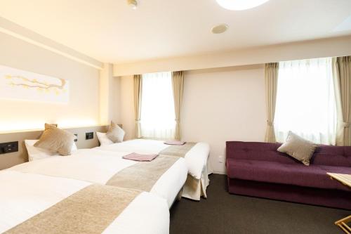 a hotel room with three beds and a couch at Inuyama Miyako Hotel in Inuyama