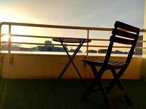 une chaise en bois assise sur un balcon avec vue sur le coucher du soleil dans l'établissement La Défense, Cozy Appartment 2 rooms, à Courbevoie