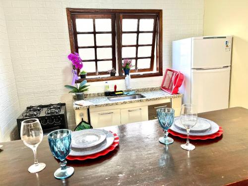 a kitchen with a table with wine glasses on it at Studio pé na areia com área de churrasco privativa in Bertioga