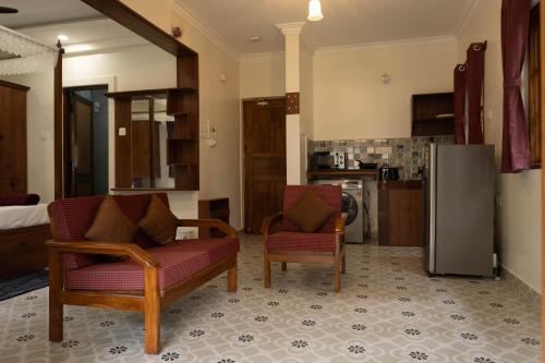 a living room with two chairs and a refrigerator at Vistar Holidays in Goa