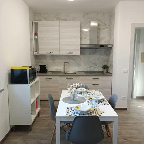cocina con mesa blanca y sillas y cocina con armarios blancos en Villa 1, en Cassano dʼAdda