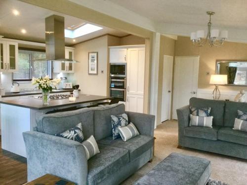 a living room with two couches and a kitchen at Luxury Forest View Lodge with private Hot Tub in Morpeth