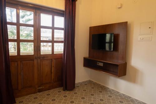 a room with a door and a tv and a window at Vistar Holidays in Goa
