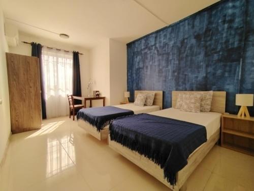 a bedroom with two beds and a blue wall at Morsky Vanek Apartment in Flic-en-Flac