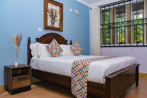 a bedroom with a bed with blue walls and windows at Casa Kalimbini in Sultan Hamud