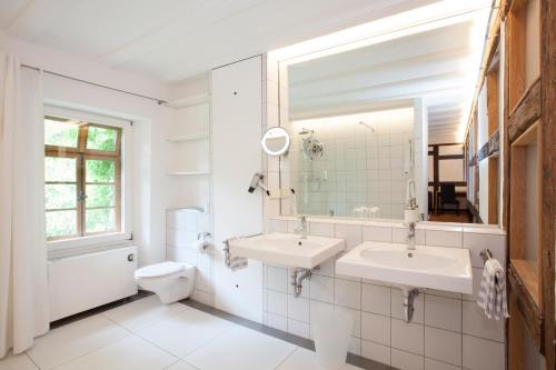 a bathroom with two sinks and a toilet and a mirror at Mühle am Schlossberg in Wartenberg-Rohrbach