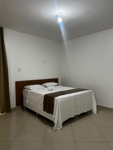 a bed in a room with a light on the ceiling at Brisas do Mar HOTEL & APART in Valença
