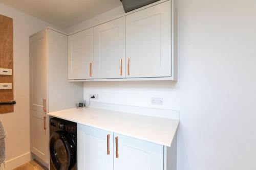 a kitchen with white cabinets and a washer and dryer at Northleigh in Chulmleigh