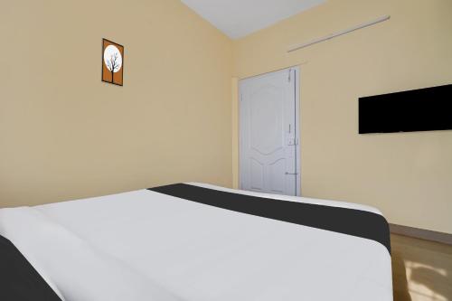 a white room with two beds and a tv at Super Hotel O Royal Rooms in Bengaluru