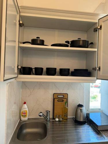 a kitchen with pots and pans on shelves above a sink at استديو انيق في قلب ابوظبي in Abu Dhabi