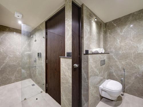 a bathroom with a toilet and a glass shower at Saltstayz Premier - Golf Course Road & Sector 42 in Gurgaon
