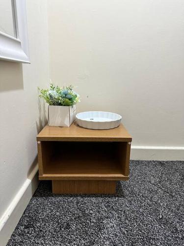 a wooden table with a plant on top of it at Airrose two bed apartment in Wolverhampton