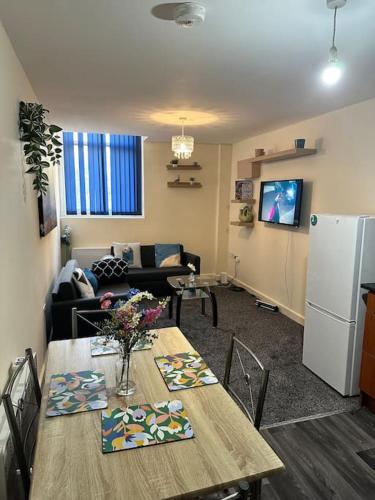a living room with a table and a refrigerator at Airrose two bed apartment in Wolverhampton