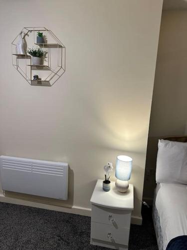 a bedroom with a bed and a night stand with a lamp at Airrose two bed apartment in Wolverhampton