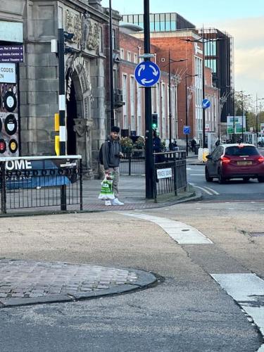 a man standing on a city street with a blue sign at Airrose two bed apartment in Wolverhampton