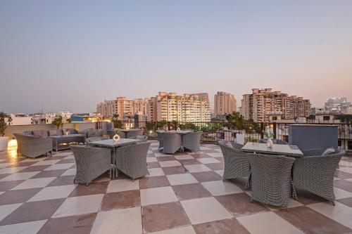 a patio with tables and chairs on a roof at Saltstayz Premier - Golf Course Road & Sector 42 in Gurgaon