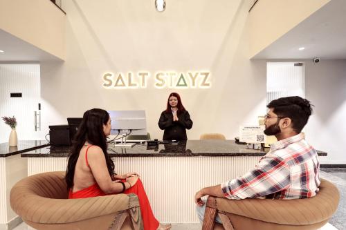 a man and woman sitting in chairs in front of a salon at Saltstayz Premier - Golf Course Road & Sector 42 in Gurgaon