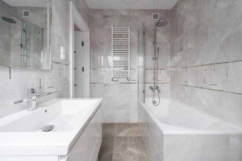 a white bathroom with a tub and a sink at Apartament Mariola in Gdańsk