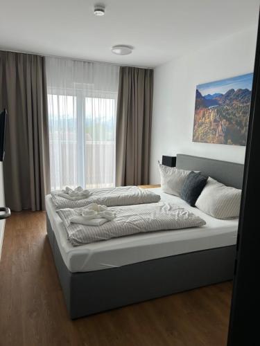 a large bed in a bedroom with a large window at Hotel Casa Maria in Halblech