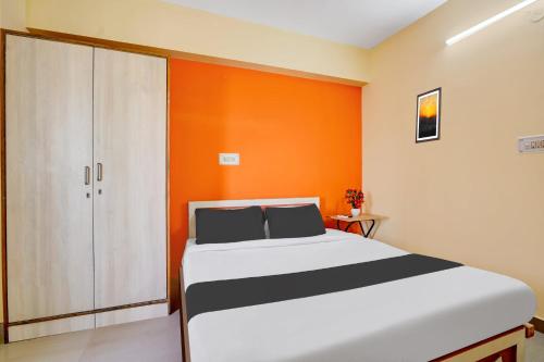 a bedroom with a bed and an orange wall at Super Hotel O Royal Rooms in Bengaluru