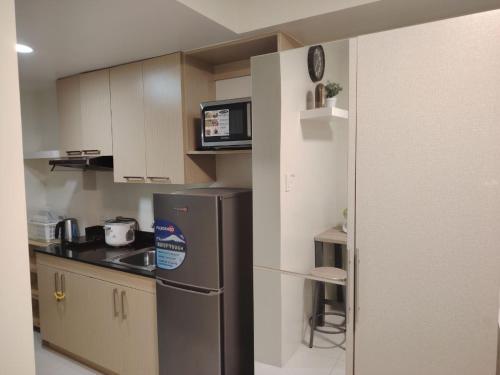 a small kitchen with a refrigerator and a microwave at CozyNest Rentals at Brenthill Condominium in Baguio