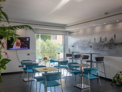 a room with tables and chairs and a tv on a wall at San Valentino Hotel in Villa di Serio