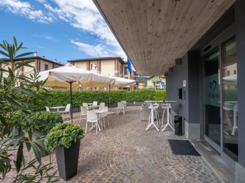 a patio with tables and chairs and an umbrella at San Valentino Hotel in Villa di Serio