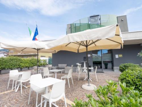 a patio with white tables and chairs and umbrellas at San Valentino Hotel in Villa di Serio