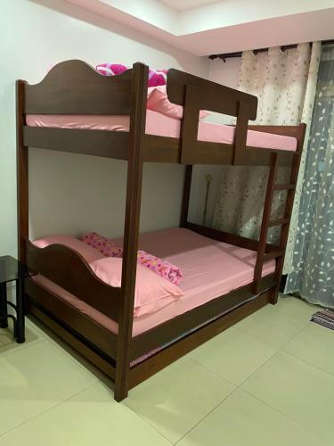 a wooden bunk bed with pink sheets on it at Arkes Residential Condo Unit Rental in Baguio