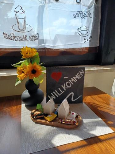 a table with a plate of food and a vase with flowers at Kleine Hummel in Soltau