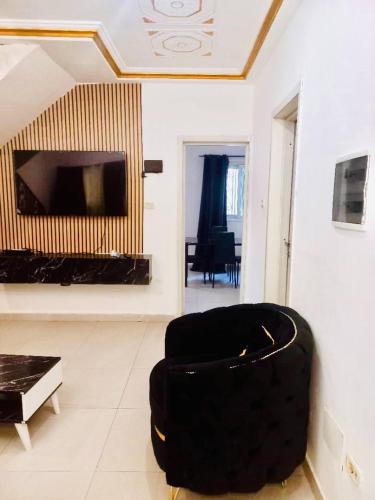 a living room with a black chair and a tv at Villa Amina splendid elegant structure in Ouagadougou