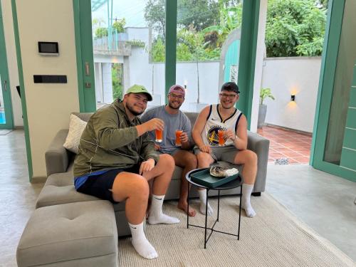a group of three people sitting on a couch at Nomad Nest in Hikkaduwa