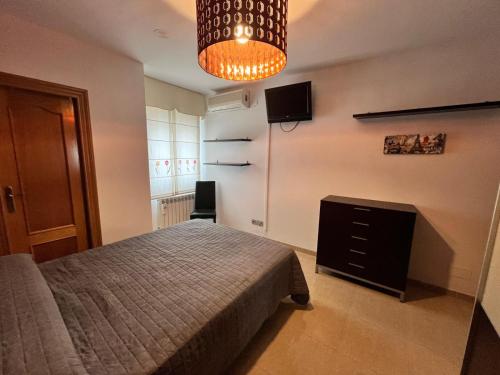 Un dormitorio con una cama, un televisor y una lámpara de araña. en Alojamiento MB Baza, en Baza