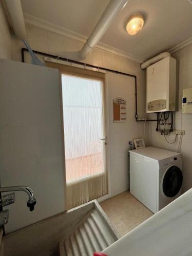 a laundry room with a washing machine and a window at Alojamiento MB Baza in Baza