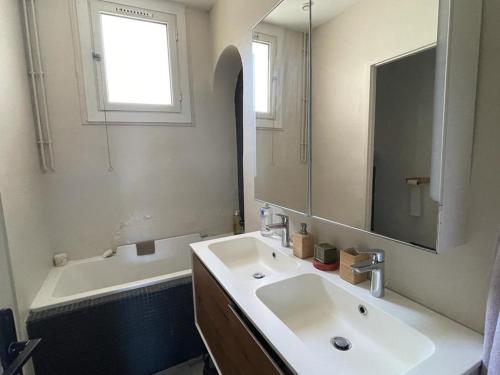 une salle de bain avec un lavabo, une baignoire et un miroir dans l'établissement Appartement de la Plage, à Marseille