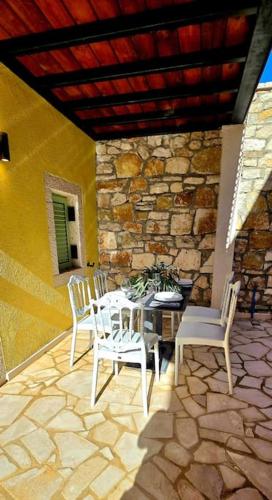 a patio with a table and chairs and a stone wall at Vista Del Mar Mansion in Spile