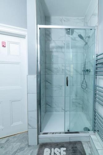 a glass shower in a bathroom with a door at Tranquil 3BR in Arnos Grove in New Southgate